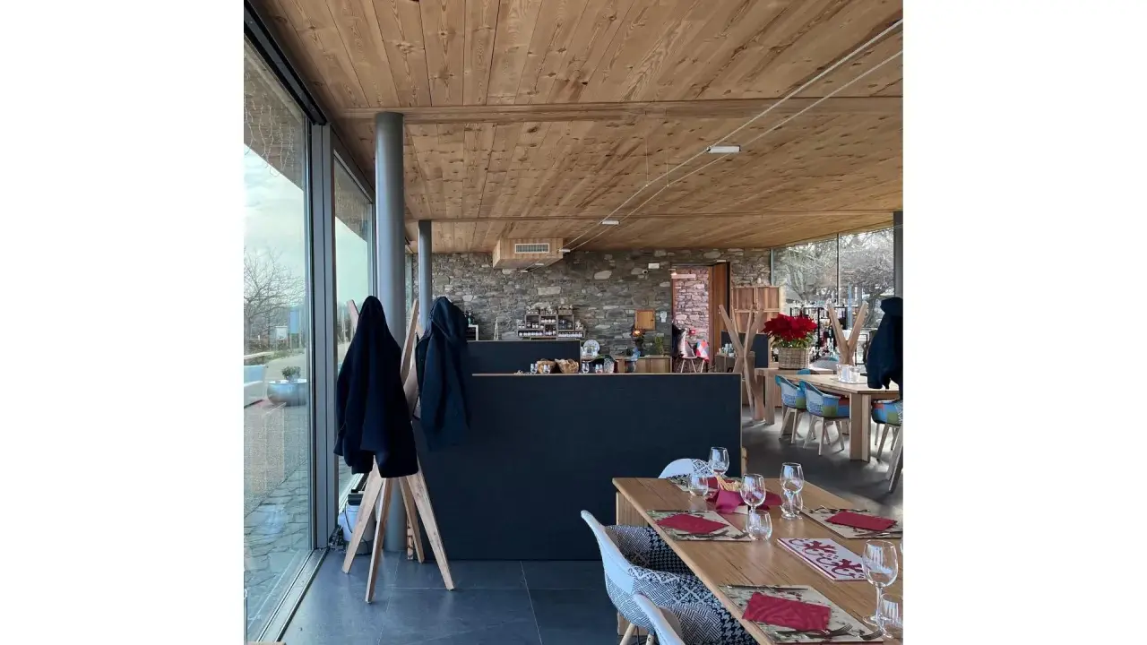 Interno di un agriturismo con tavoli apparecchiati, bancone in pietra e legno. L'agriturismo acqua terra sole offre un'atmosfera accogliente.