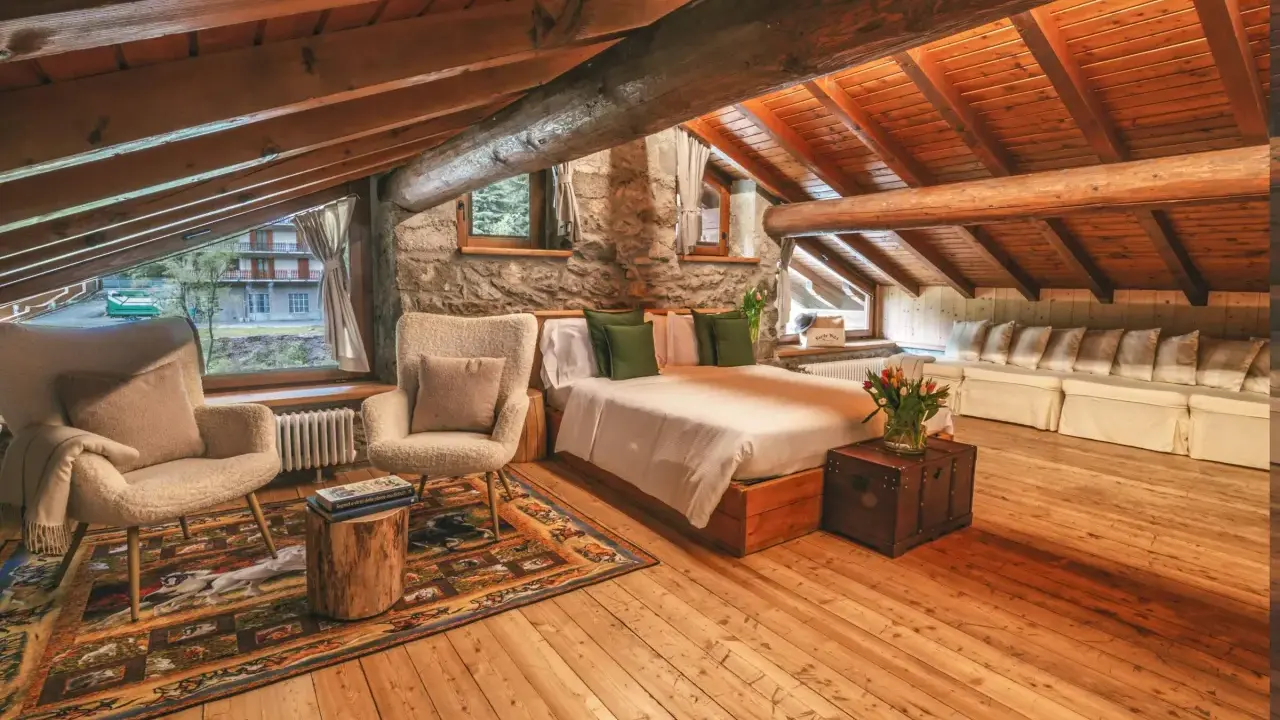 Accogliente camera con camino, travi in legno a vista, letto comodo, poltrone soffici e un tappeto decorato.