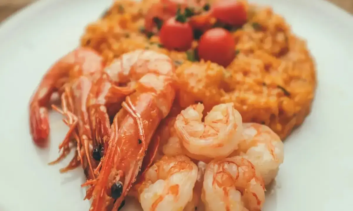 Risotto rosso con gamberi, un piatto tipico di Pavia, guarnito con pomodorini freschi.