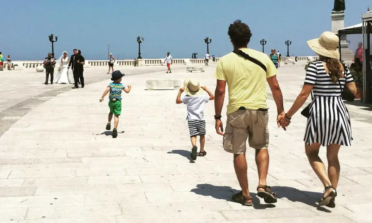 Famiglia in vacanza in Puglia con bambini, mentre passeggiano sul lungomare.