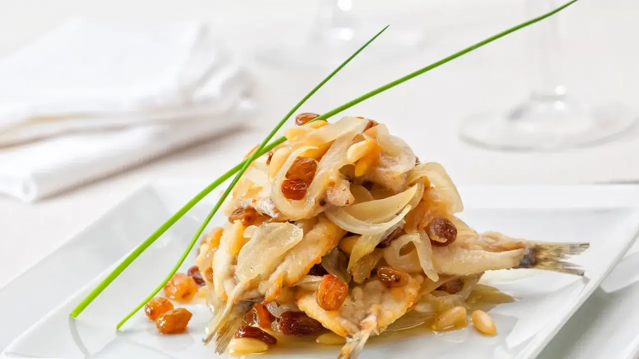 Sardine in saor, un classico dei piatti tipici veneti, con cipolle caramellate, uvetta e pinoli.
