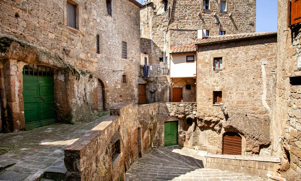 Un vicolo stretto con scale di pietra e case antiche in tufo, un'atmosfera da piccola Gerusalemme.