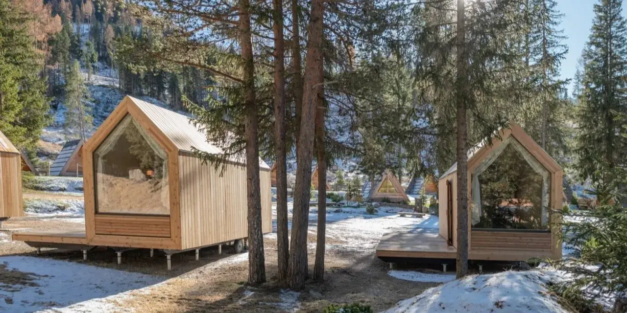 Accoglienti alloggi particolari nel Lazio, con cabine in legno e ampie vetrate immerse nel bosco innevato.