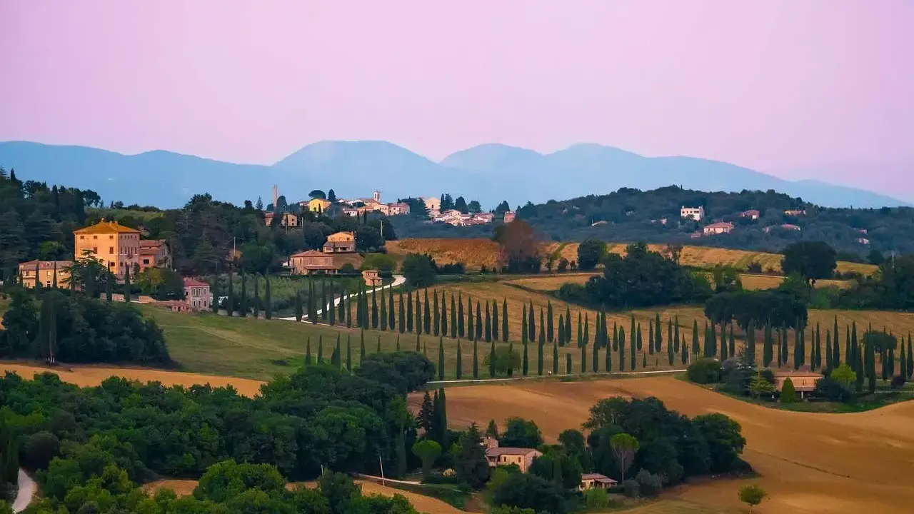 Dolci colline umbre con cipressi e casali, un paesaggio ideale per una vacanza in Umbria con bambini.