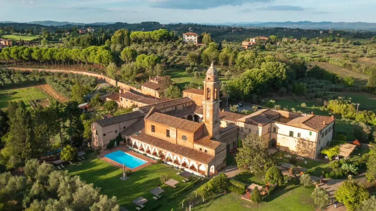 Un'antica dimora con campanile e una splendida piscina toscana, immersa nel verde delle colline.
