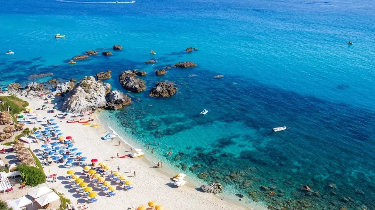 Spiaggia calabrese con ombrelloni colorati e mare cristallino, ideale tra i posti da visitare in Calabria con bambini per una vacanza indimenticabile.