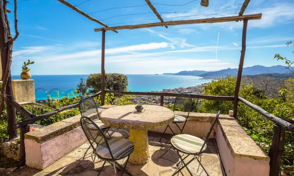Terrazza con tavolo e sedie, vista mare e colline. Ideale per agriturismi entroterra ligure.