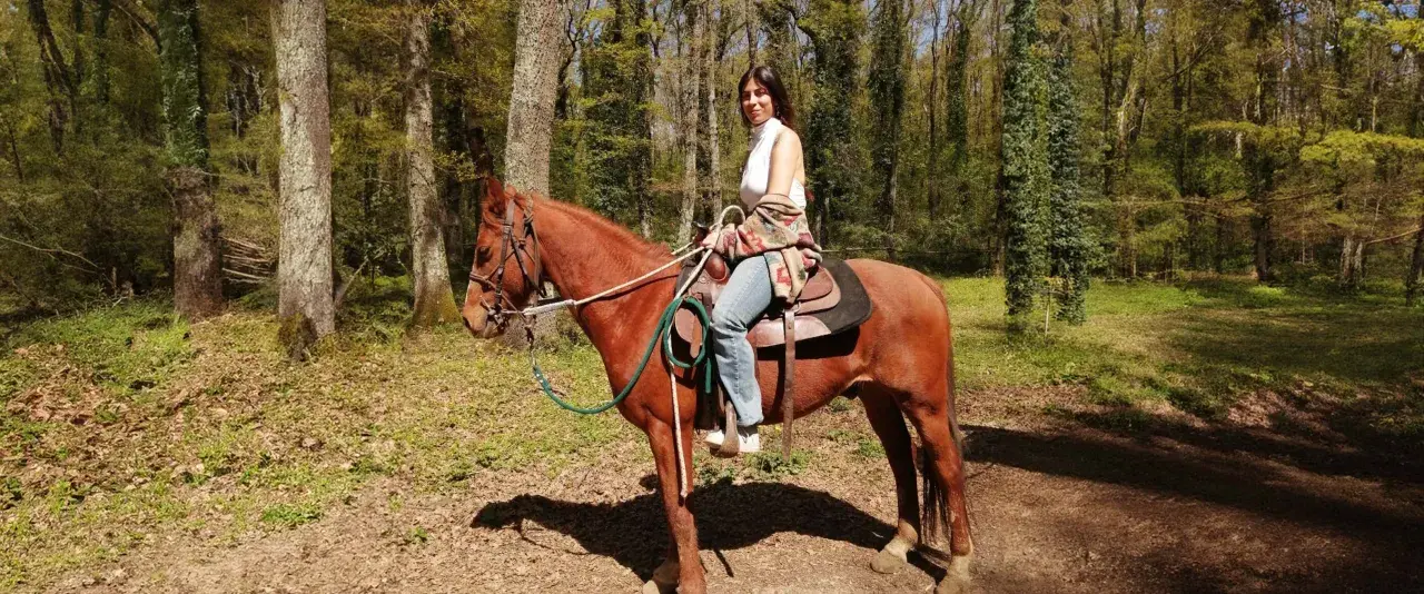 Donna a cavallo in un bosco del Lazio, godendosi una tranquilla passeggiata a cavallo.