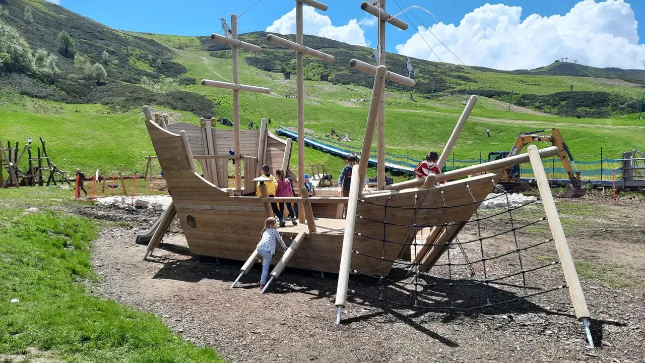 Un grande galeone di legno su un prato verde, perfetto per agriturismi per bambini in Piemonte. Bambini giocano a bordo.