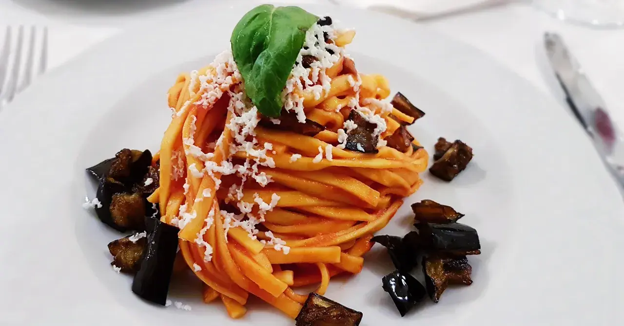 Pasta con melanzane fritte e ricotta salata, un classico su cosa mangiare in Sicilia. Un piatto gustoso e colorato.