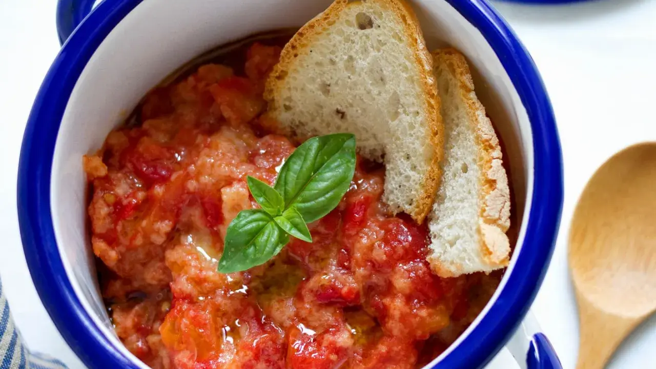 Pappa al pomodoro, un piatto che racconta la sua origine toscana. Servita in ciotola con pane raffermo, pomodoro e basilico fresco.