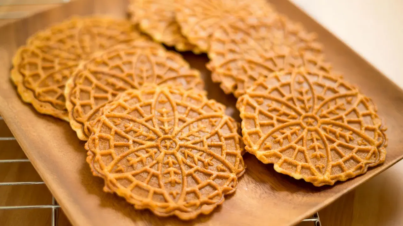 Pizzelle, dolci tradizionali abruzzesi, su un piatto di legno.