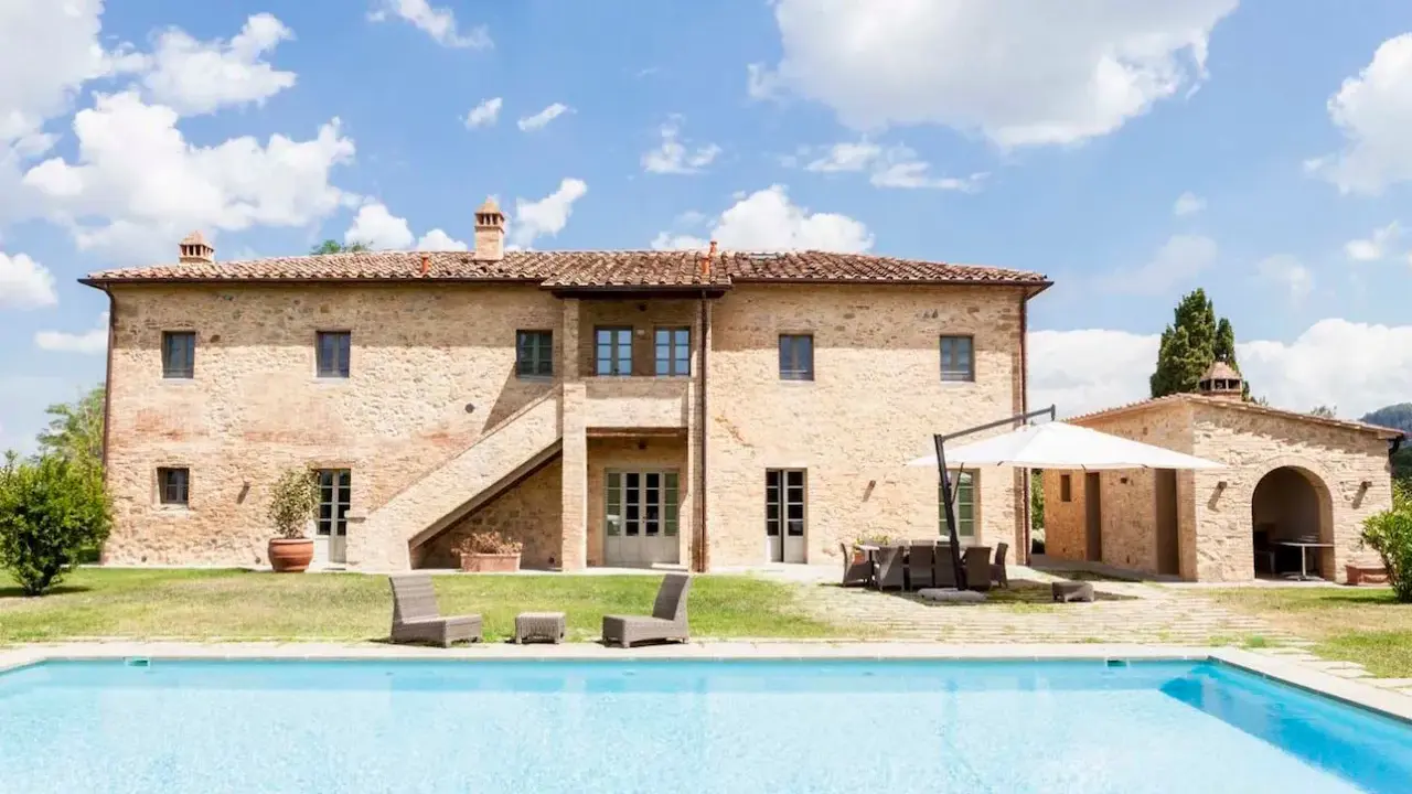 Splendida villa in pietra con piscina, un sogno di masserie toscane sotto un cielo azzurro.