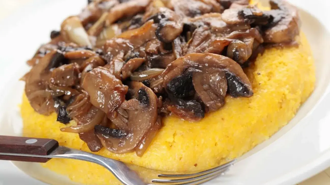 Polenta con funghi trifolati, un classico tra i cibi tipici del Trentino Alto Adige, pronta per essere gustata.