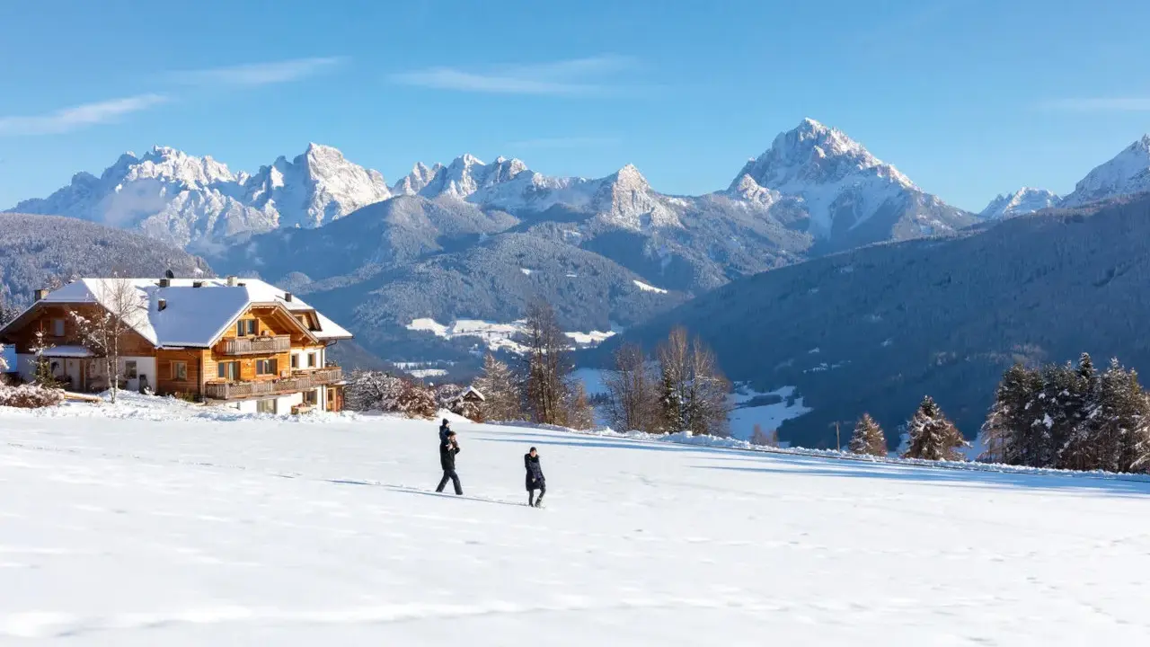 Un agriturismo con un gallo rosso sul tetto, immerso in un paesaggio innevato con montagne maestose.