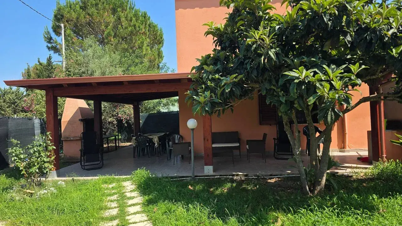 Veranda con tavolo e sedie, barbecue e alberi da frutto. Un angolo di pace tra i migliori agriturismi Sardegna sud.