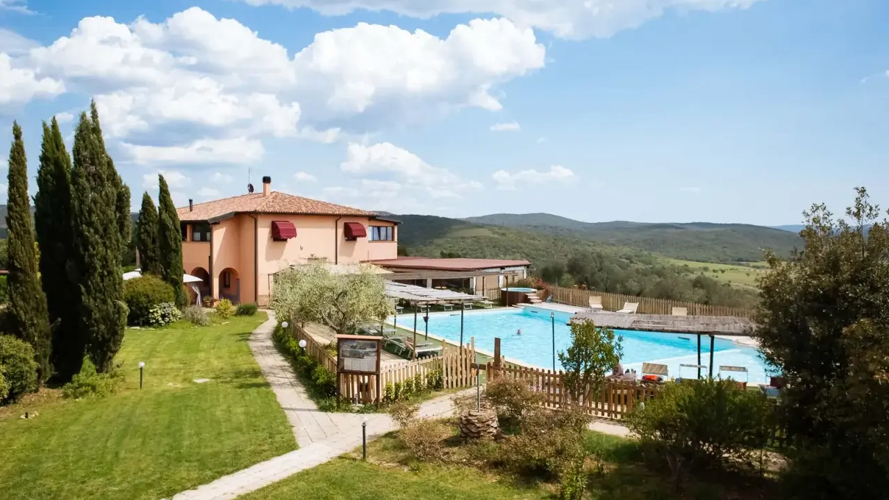 Un agriturismo in Toscana a Pasqua, con piscina azzurra e colline verdi sullo sfondo.