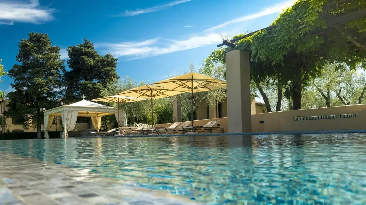 Piscina con lettini e ombrelloni in un agriturismo particolare nel Lazio, immerso nel verde.