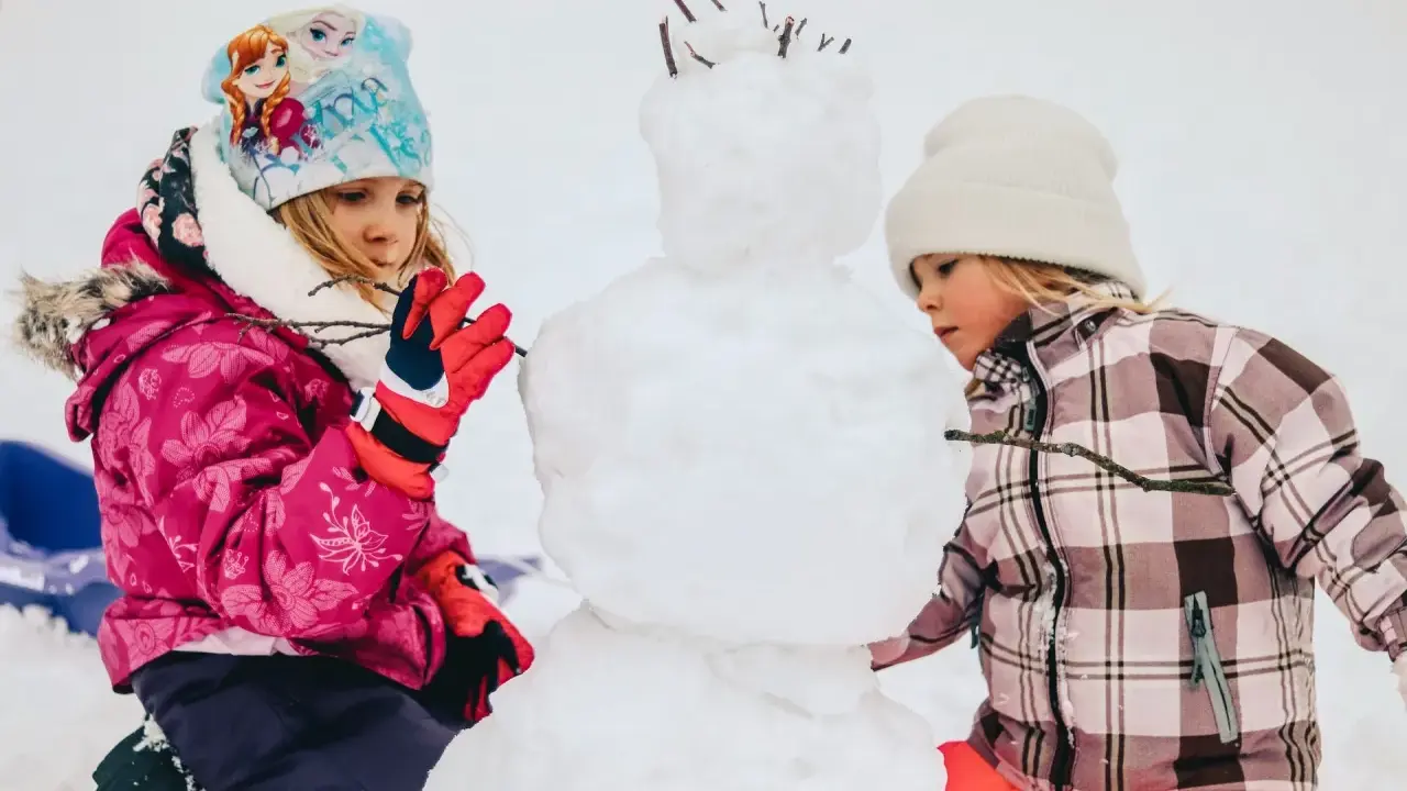 Bambini creano un pupazzo di neve in montagna, un vero natale in montagna con bambini che si divertono nella neve.
