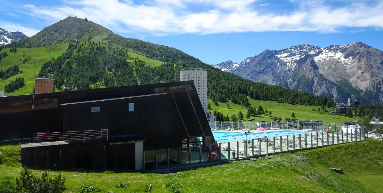 Una splendida piscina in montagna in Piemonte, con vista su verdi colline e cime innevate.