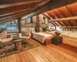 Accogliente camera con camino, travi in legno a vista, letto comodo, poltrone soffici e un tappeto decorato.