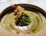 Un nido di spaghetti verdi con verdure e carne, guarnito con un fiore rosso. Un assaggio dei piatti tipici Avellino.
