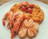 Risotto rosso con gamberi, un piatto tipico di Pavia, guarnito con pomodorini freschi.