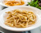 Pici cacio e pepe, un classico tra i piatti tipici di Siena, serviti su un piatto bianco.
