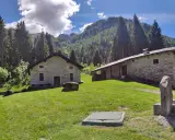 Agriturismi lombardia montagna: casette in pietra immerse nel verde, con boschi e montagne sullo sfondo.