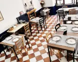 Tavoli apparecchiati in un ristorante, pronti per un'esperienza di **mangiare in Umbria**. Pavimento a scacchi, sedie in legno e dettagli eleganti.