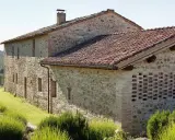 Un casale in pietra e mattoni, ideale per vacanze in Umbria montagna, immerso nel verde con tetto in coppi e un muro traforato.