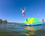 Bambini si divertono sul lago Trasimeno, uno salta da un gonfiabile mentre un altro si riposa.