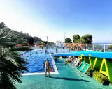 Sole, piscina e divertimento al camping Riva Verde Marche. Famiglie e bambini si godono l'acqua cristallina e il relax sotto gli ombrelloni.