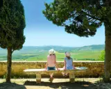Due bambine con cappello ammirano il panorama collinare toscano, un perfetto weekend con bambini in Toscana.