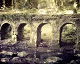 Antica struttura in pietra con archi, forse un acquedotto o un ponte, immersa nel verde. La **vitozza Sorano** sembra un luogo dimenticato dal tempo.