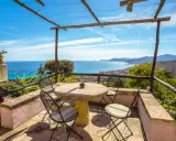 Terrazza con tavolo e sedie, vista mare e colline. Ideale per agriturismi entroterra ligure.