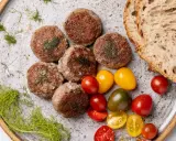 Polpette di cinta senese su piatto rustico, con pomodorini colorati, pane casereccio e finocchietto selvatico.