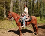 Donna a cavallo in un bosco del Lazio, godendosi una tranquilla passeggiata a cavallo.