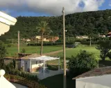 Un angolo di pace tra gli agriturismi in Calabria. Un pergolato bianco con tavolino e sedie blu, circondato da verde e colline rigogliose.