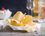 Delicati cialde, un dolce tipico toscano, su un tovagliolo ricamato. Sullo sfondo, una ciotola con crema e bicchieri.