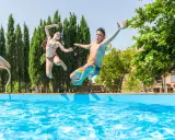 Bambini che saltano in piscina, una gioiosa Pasqua in Toscana tra cipressi e sole.