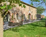 Antica locanda nel Val di Chiana, con tavoli all'aperto e un prato fiorito.