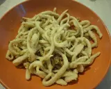 Pici fatti in casa con un saporito sugo per i pici, serviti in un piatto arancione.