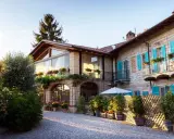 Un incantevole agriturismo in Piemonte, con un cortile acciottolato, balconi fioriti e persiane azzurre.