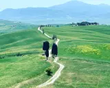 Un sentiero serpeggia tra le dolci colline verdi della Val d'Orcia, ideale per un indimenticabile trekking.