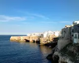Scogliere bianche e case a picco sul mare blu, un'ottima idea per cosa visitare vicino Alberobello.