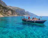 Gente in barca per un'esperienza di pescaturismo, con acque cristalline e costa rocciosa sullo sfondo.