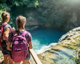 Due ragazze con zaini ammirano una cascata durante un trekking in Toscana montagna.
