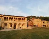 Edificio storico con portico ad archi, un pozzo e persone che passeggiano. Un luogo che sembra uscito da uno dei tanti film girati a Montepulciano.