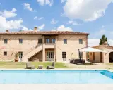 Splendida villa in pietra con piscina, un sogno di masserie toscane sotto un cielo azzurro.